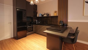 A modern kitchen with a central island, dark cabinetry, and pendant lighting. - Grandstay Apartments 001 (Durrës)