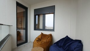 A balcony with a sliding door, a window with a roller blind, and two bean bags. - Grandstay Apartments 001 (Durrës)