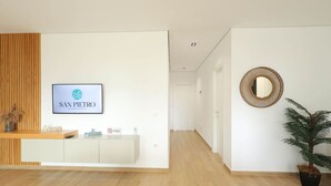 Un espace d’accueil avec une enseigne indiquant « SAN PIETRO Vacation Rentals », un comptoir de réception en bois, une plante en pot et un miroir rond accroché au mur.
