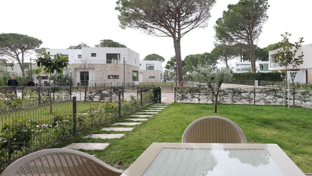Une cour avec une table et des chaises, entourée d’une clôture et d’arbres.