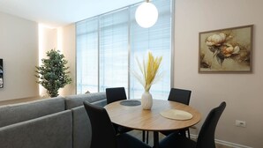 Un comedor moderno con una mesa redonda, sillas negras, un sofá gris, una planta en maceta y un cuadro en la pared.