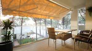 Ein Balkon mit Tisch und Stühlen, einem Blumentopf und Blick auf einen Innenhof mit Bäumen und Gebäuden.