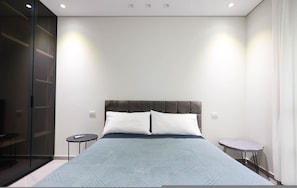 Ein modernes Schlafzimmer mit einem großen Bett, zwei Nachttischen und einer Glastrennwand.