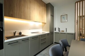 A modern kitchen with a wooden upper cabinet, a stainless steel sink, and a countertop with a coffee maker. - Sanpietro Vacation Apartment 004 (Ishëm)