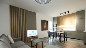 Ein modernes Wohnzimmer mit einer Couch, einem Fernseher und einem Essbereich mit Stühlen und einem Tisch.