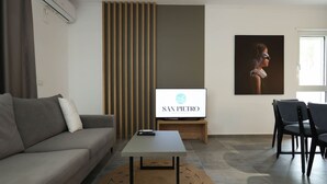Ein modernes Wohnzimmer mit Sofa, Couchtisch, Fernseher auf einem Lowboard und einem gerahmten Bild an der Wand.