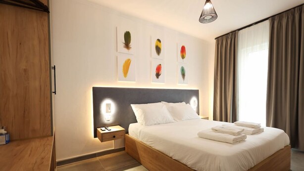 Ein modernes Hotelzimmer mit einem hölzernen Bett, einem Nachttisch mit Telefon und Wandbildern.