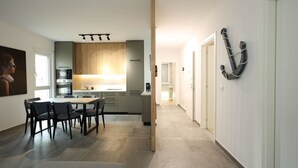 Eine moderne Küche mit Holzausstattung, ein Essbereich mit Tisch und Stühlen sowie ein Flur mit dekorativem Anker an der Wand.