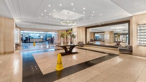 A spacious lobby with a reception desk, a chandelier, and a seating area. - High Rise | Premium Amenities | BayView | StayCozy (Miami)
