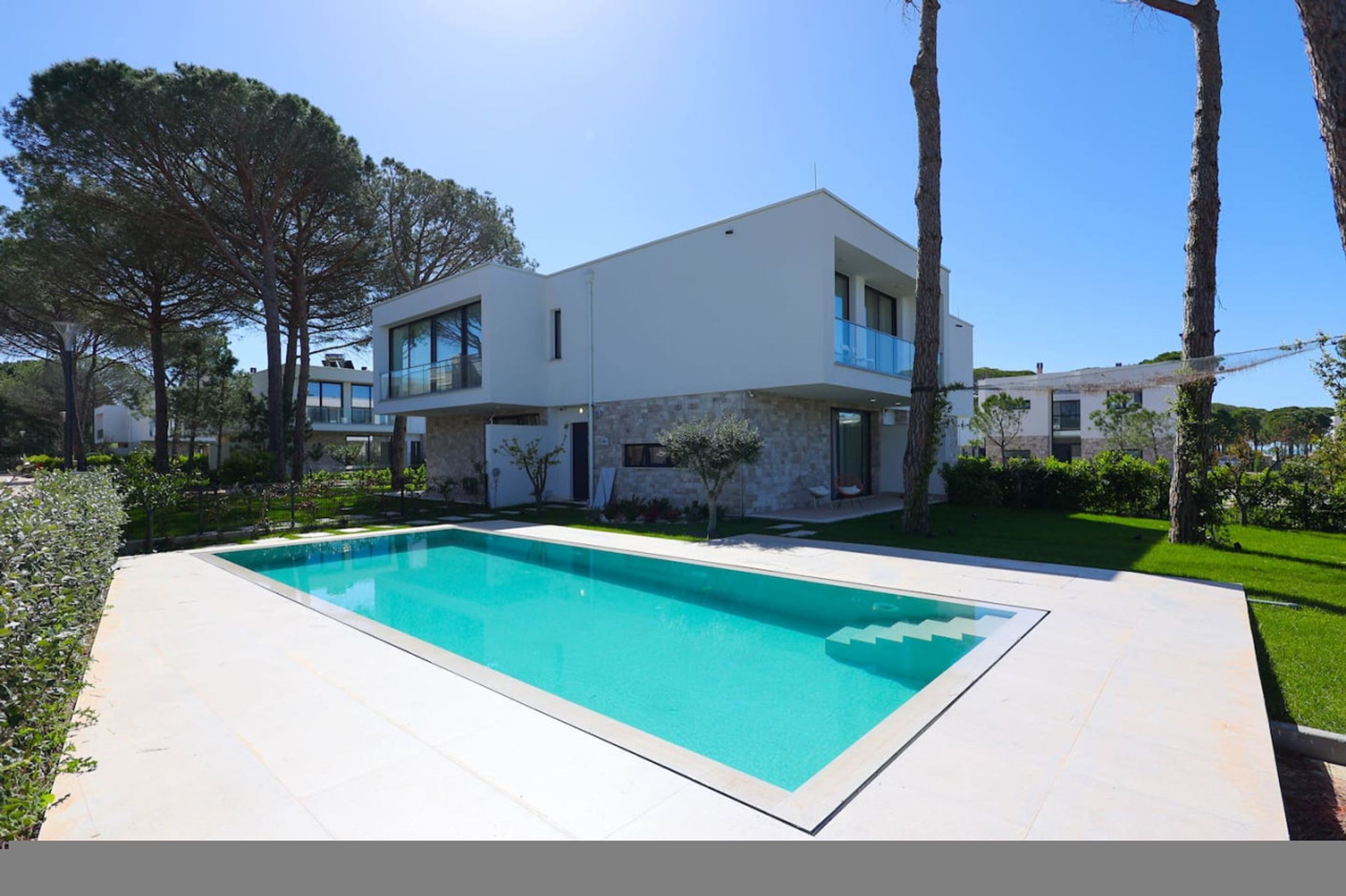 A modern two-story house with a swimming pool in the foreground.