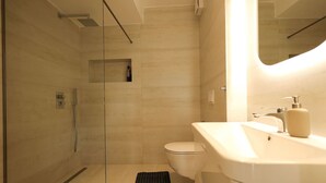 Une salle de bain moderne avec une douche à parois de verre, des toilettes et un lavabo avec un miroir.