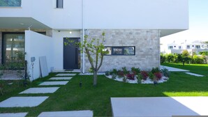 Une maison moderne à deux étages, dotée d’une façade en pierre, d’un petit jardin agrémenté de pas japonais et surplombée d’un ciel dégagé.