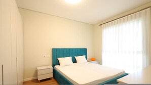 Een slaapkamer met een bed, nachtkastje en gordijnen.