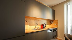 Een moderne keuken met grijze kastjes, een houten aanrecht, een spoelbak, een koffieapparaat en een vaatwasser.