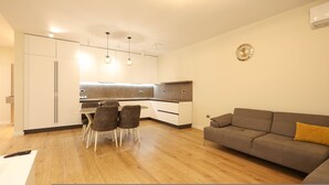 Een moderne keuken met witte kasten, een eettafel met stoelen, en een bank in een zithoek.