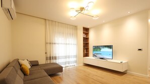 Een moderne woonkamer met een bank, televisie en ingebouwde kasten.