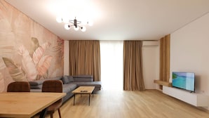 A modern living room with a sofa, a coffee table, a TV on a white stand, and a wooden floor. - Sanpietro Vacation Apartment 009 (Ishëm)