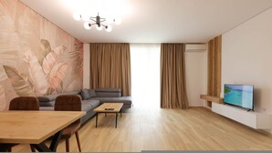 Een moderne woonkamer met een bank, een eettafel en een tv op een dressoir.