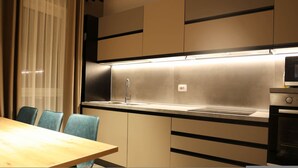 A modern kitchen with a stainless steel sink, a microwave, and a dining area with a table and chairs. - Sanpietro Vacation Apartment 011 (Ishëm)