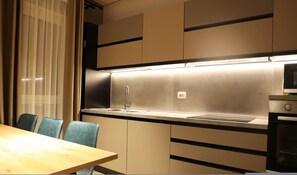 A modern kitchen with a stainless steel sink, a microwave, and a dining area with two chairs. - Sanpietro Vacation Apartment 011 (Ishëm)
