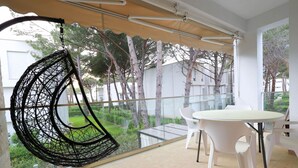 A modern balcony with a hanging chair, a round table, and chairs. - Sanpietro Vacation Apartment 011 (Ishëm)