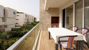 Un balcon avec une table et des chaises, un mur en pierre et une vue sur les bâtiments voisins.