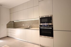 Eine moderne Küche mit integrierten Geräten, darunter eine Mikrowelle und ein Backofen, sowie ein Spülbecken aus Edelstahl.