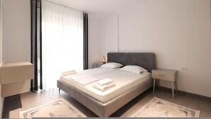 Une chambre moderne avec un grand lit, des tables de chevet, une commode et une fenêtre avec des rideaux.