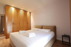 A bedroom with a large bed, wooden wardrobes, and a small bedside table. - Sanpietro Vacation Apartment 014 (Ishëm)