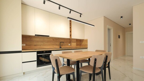 Eine moderne Küche mit Holzarbeitsplatte, schwarzen Schränken und einem Essbereich mit Holztisch und Stühlen.