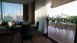Un espace repas moderne comprenant une table et des chaises, un canapé et une vue sur l’extérieur.