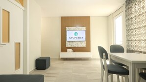 Une chambre d’hôtel moderne avec un coin repas, un téléviseur fixé sur un panneau en bois et un rideau à motifs.