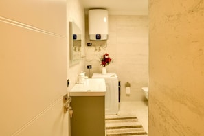 Ein Badezimmer mit Waschbecken, Spiegel, Toilette und Handtuchhalter.