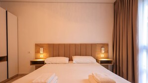 Une chambre d’hôtel avec un grand lit, deux tables de chevet avec des lampes et une armoire.