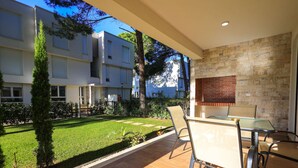 Un appartement moderne doté d’un balcon, d’un coin repas avec une table et des chaises en verre, et d’un mur en pierre.