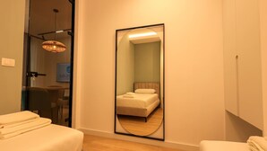 A hotel room with a large mirror reflecting a bed and a bathroom. There is a wooden floor and a ceiling light fixture. - Sanpietro Vacation Apartment 027 (Ishëm)