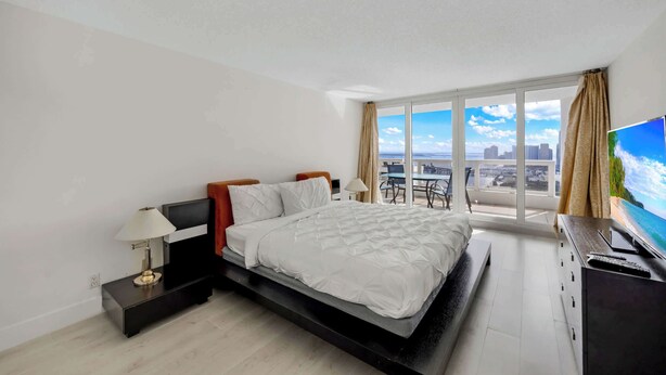 Un dormitorio moderno con una cama grande, televisión y vistas de la ciudad.
