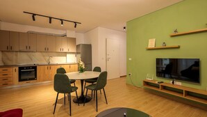 Eine moderne Küche mit Holzausstattung, einem Esstisch mit Stühlen, einem eingebauten Backofen und einem an der Wand montierten Flachbildfernseher.