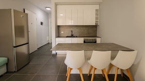 A modern kitchen with white cabinets, a stainless steel refrigerator, a central island with chairs, and a tiled floor. - Sanpietro Vacation Apartment 030 (Ishëm)