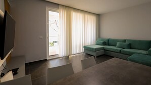 A modern living room with a sectional sofa, a flat-screen TV, and a dining area. - Sanpietro Vacation Apartment 030 (Ishëm)