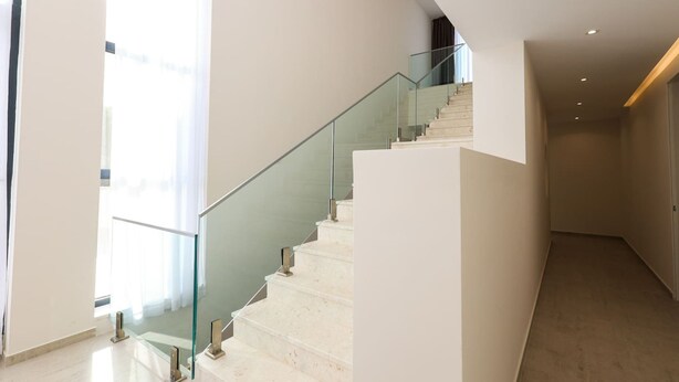 A modern staircase with glass railings, leading to an upper floor.