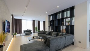 A modern living room with a sectional sofa, a coffee table, and a built-in black shelving unit.