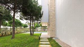 A modern building with a stone facade and a pathway leading to a pool area.