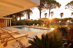 A pool area with lounge chairs and umbrellas, surrounded by trees and a well-maintained lawn. - Sanpietro Elite Signature Villa (Ishëm)