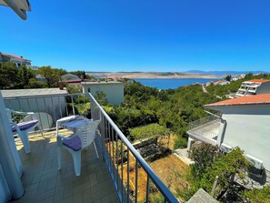A balcony with a view of the sea, surrounded by greenery and buildings. - Apartment Asta (Jadranovo)