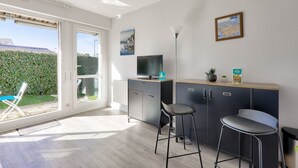 A modern kitchen with a large window, a television, and two bar stools.