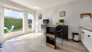 A modern kitchen with a dining area, a TV, and a view of the garden.