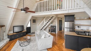 A spacious loft with a high ceiling, a staircase to an upper level, a kitchen with modern appliances, and a cozy seating area with a couch and coffee table. - Chalet on Ski Mountain - Stunning Views of Mount LeConte - Right in Gatlinburg! (Gatlinburg)