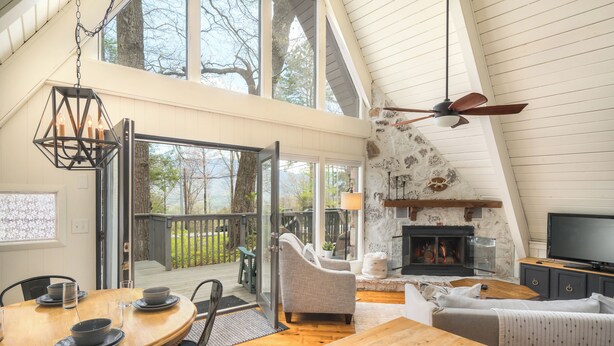 A spacious living area with a wooden dining table, comfortable seating, a fireplace, and a television. - Chalet on Ski Mountain - Stunning Views of Mount LeConte - Right in Gatlinburg! (Gatlinburg)