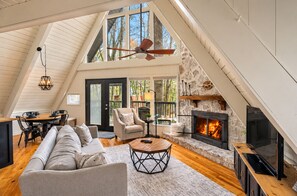 Un loft spacieux avec de hauts plafonds, une cheminée, un coin repas et une grande fenêtre donnant sur les arbres.